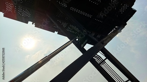 Close-up low-angle view of an old industrial vehicle showing a hydraulic lifting mechanism, steel frame, and weathered metal components against the sky