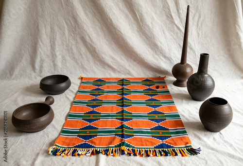 Handwoven african textile with geometric pattern and traditional pottery on a white background, the collection of cultural artifacts includes various ceramic bowls and vases, ethnic craftsmanship