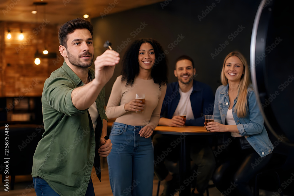 Fototapeta premium Friends Playing Darts in Warm Indoor Setting