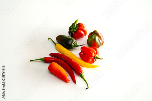 Картината върху платно A vibrant variety of fresh chili and sweet peppers in red yellow and green arranged on a bright white background a colourful assortment of spicy vegetables and cooking ingredients