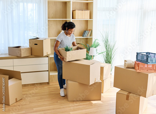 Fotografie Portrait of ayoung woman girl unpacking boxes after moving in and relocation in
