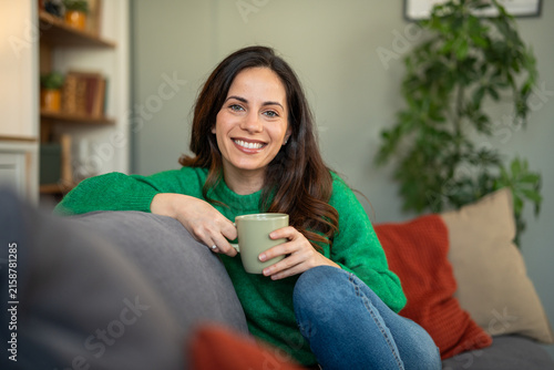 фотографія Smiling woman relaxing on couch holding mug