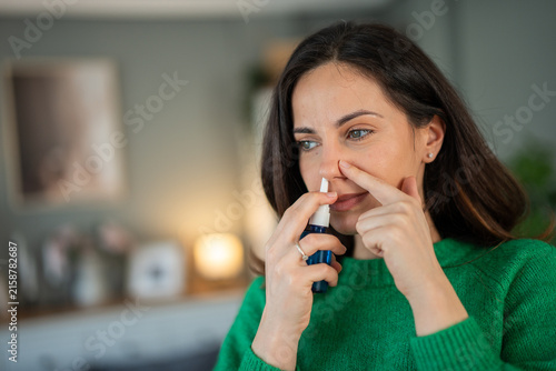 Принти на полотні Woman using nasal spray for allergy relief at home