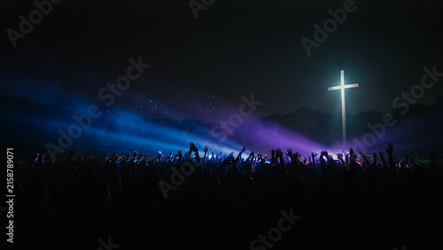 Christian music event with crowd raising hands before glowing cross