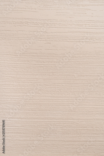 Clean close-up of a decorative plaster wall surface with fine horizontal stripe relief pattern in warm beige and cream tones, suitable as a minimal background