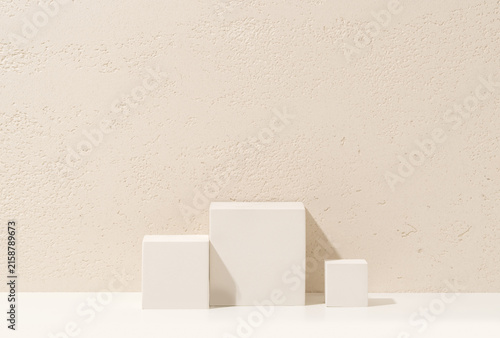 White Cube Podiums of Different Heights on White Shelf Against Travertine Wall Background