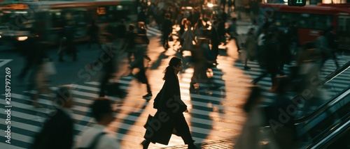 Pedestrians cross a busy urban street at night during peak commute hours.
