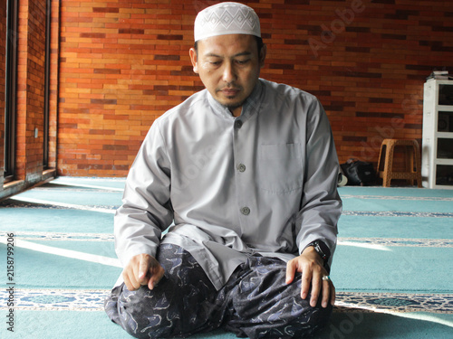 Quadro su tela Close up of Asian man body who is praying in sitting recitation or tahiyat sit s