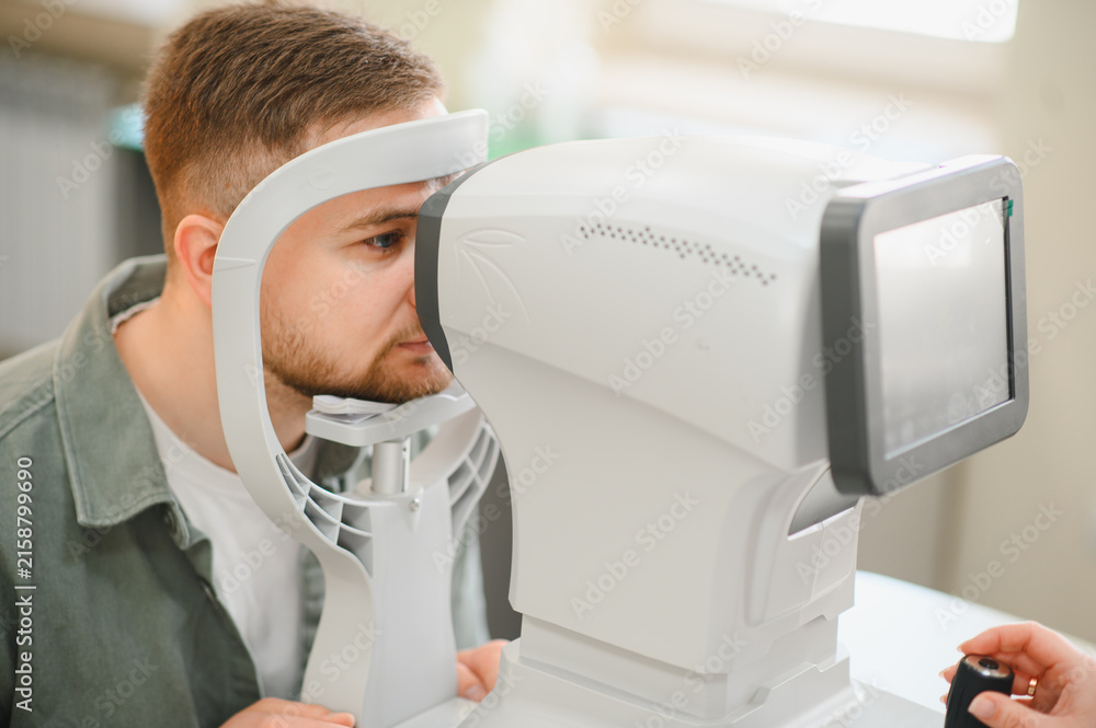 Obraz premium Man having eye exam with optometrist diagnostic equipment
