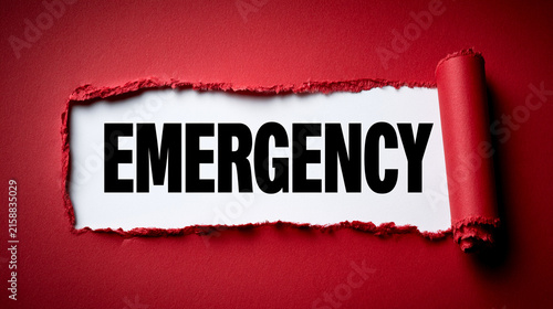 The word emergency written in black letters on a white paper strip revealed by tearing a red paper background