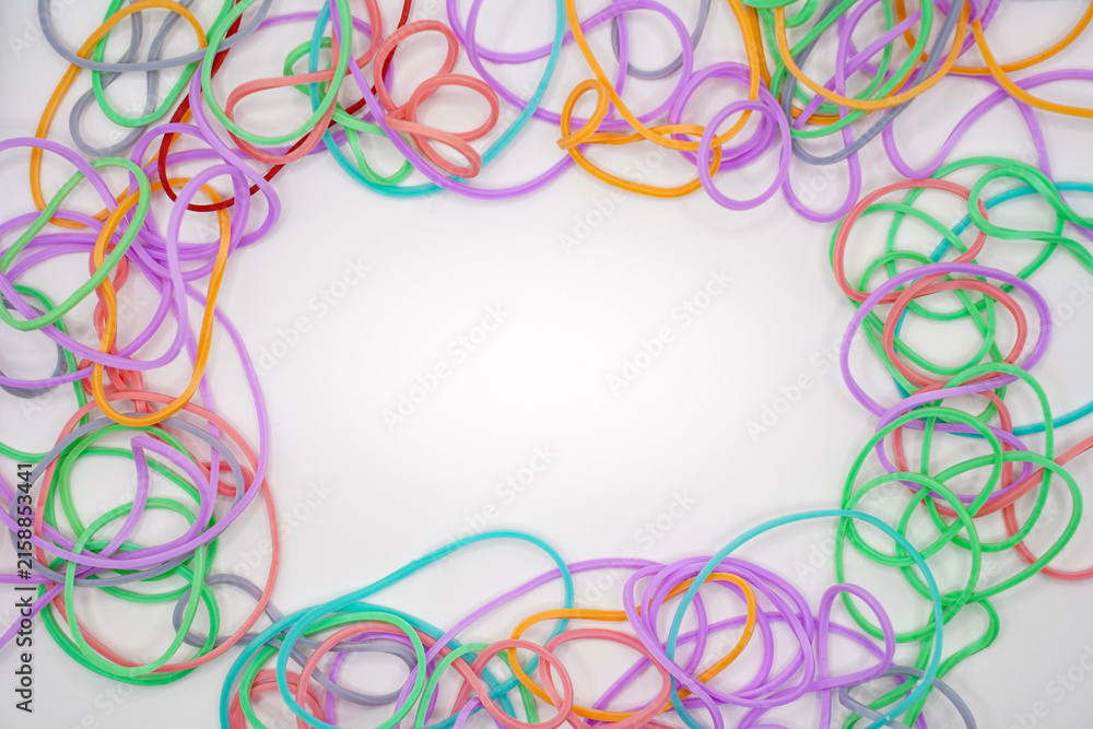 Fototapeta premium Colorful rubber bands forming a frame on a white background with copy space.