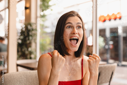 Fotografie Ecstatic Caucasian woman celebrating success holding raised fists shouting looki