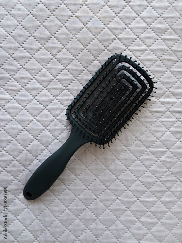 Black Hair Brush on Light Quilted Fabric Background