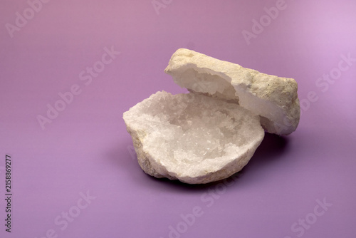 Two natural white quartz geode halves with sparkling crystal druse on a purple background.
