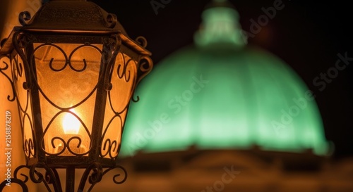 Vintage Lantern Illuminated at Night with Blurred Green Dome Background.