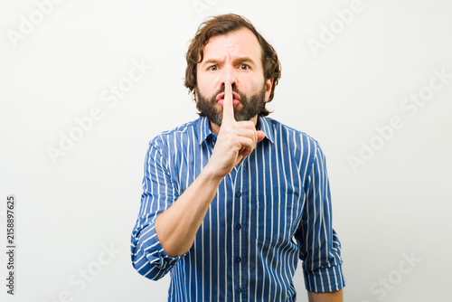 Canvas Print Man asking for discretion with a finger on his lips, signaling quiet and keeping