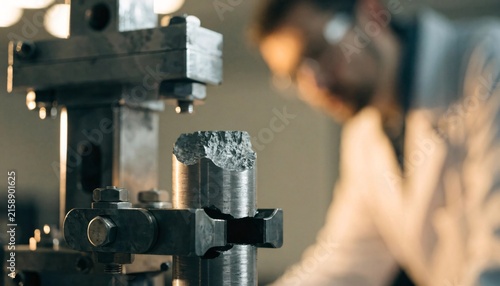 Industrial engineer inspecting a metal specimen under stress test in a metallurgy lab