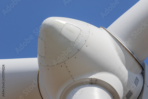 Close-up of wind turbine hub and blade connection against blue sky – renewable energy technology photo