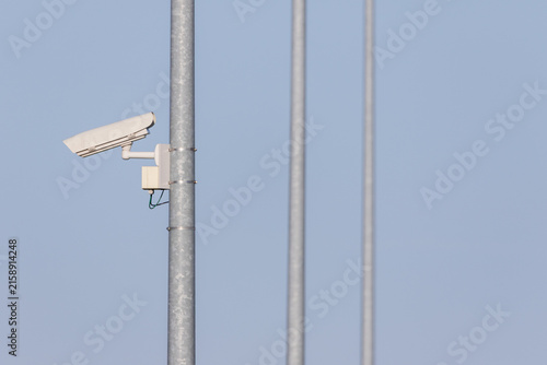 CCTV security camera mounted on metal pole against clear blue sky – surveillance and public safety photo