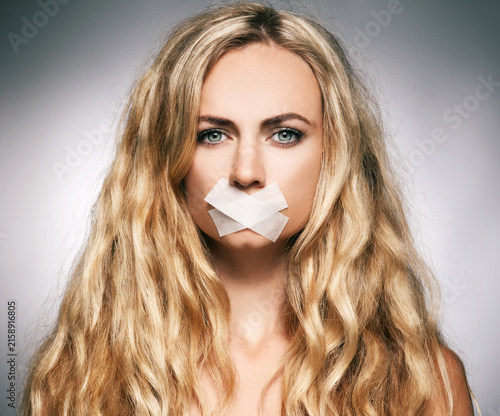 Konstfotografi Woman with adhesive tape covering her mouth in a dramatic portrait symbolizing c