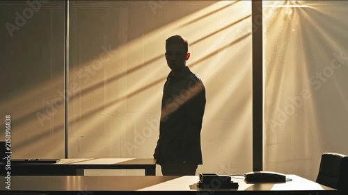 Person stands in an office with sunlight shining through the windows during the day