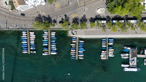 Canvas Print Top-down view of boats moored along the waterfront in Zurich, Switzerland, with clear green-blue water, docks, tree-lined streets, public transport and urban infrastructure