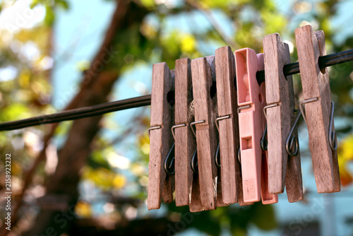 Obraz na płótnie Row of vintage wooden clothespins and one pink plastic peg on a clothesline outd