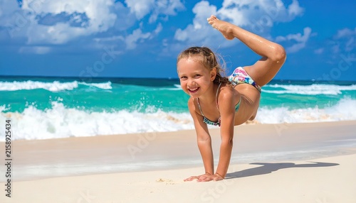 Playful Young Girl Crawling on Beach in Colorful Swimsuit