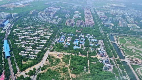 The densely developed urban area includes tree-lined neighborhoods, high-rise buildings, roads, and a large landscaped park. Winding pathways, water channels, and circular garden structure.