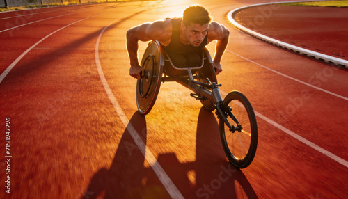 Paralympic athlete training with wheelchair on athletics track. Determination, sunset
