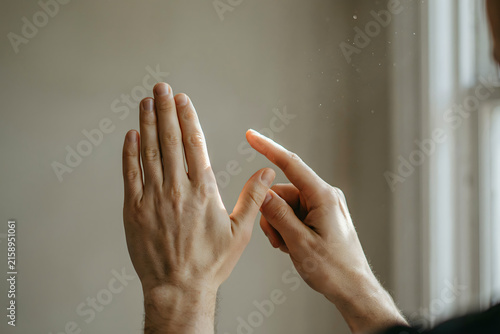 Close up of two hands performing a sign language gesture with fingers extended and touching in a bright room with soft natural window light
