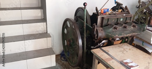 Quadro su tela Horizontal View of a Vintage Platen Press Machine Next to a Tiled Staircase in a