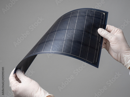 柔軟に曲がるフィルム型太陽電池を両手で持つ様子、日本産ペロブスカイト太陽電池の技術力 / Hands holding and bending a flexible film-type solar panel, showcasing made-in-Japan perovskite solar cell technology