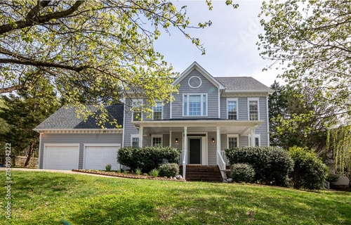 Suburban Two Story Gray House Exterior with Gabled Roof and Lush Front Lawn during Sunny Spring Season