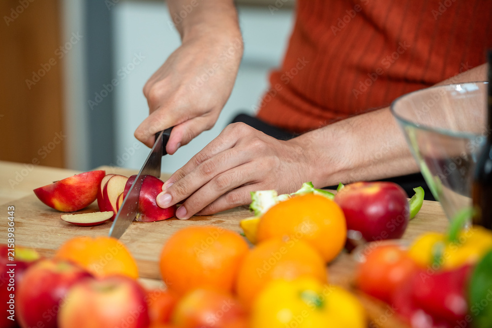 Fototapeta premium Hand chef knife cut and slice fresh Vegetables baby cos salad on wood board table .Make Salad Organic Vegetables mix lunch with vegetables and fruit at kitchen table on wood cutting board.