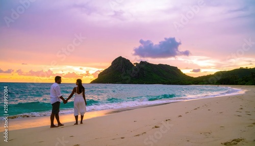 Couple enjoying sunset stroll on tropical sand beach.