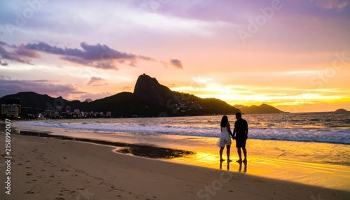 Couple holding hands on Ipanema beach at sunset in Rio