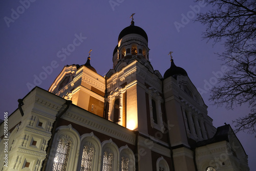 Low-angle view of the illuminated Alexander Nevsky Cathedral with onion domes and ornate exterior details against dusk sky in Tallinn