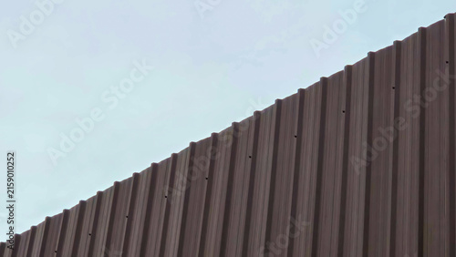 Bild auf Leinwand Towering Brown Metal Sheet Wall Under Cloudy Sky