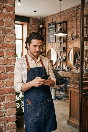 Professional barber using smartphone in a modern barbershop