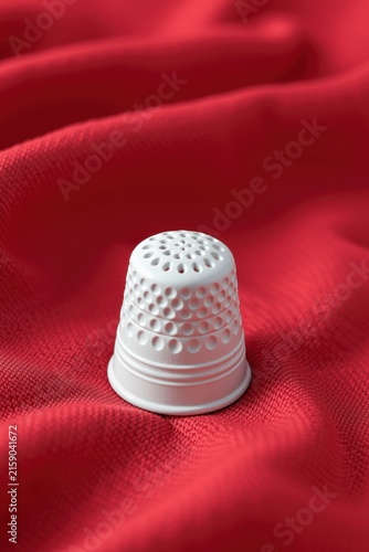 White thimble rests on vibrant red fabric