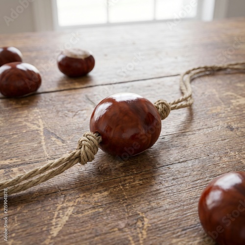 Obraz na płótnie Single Glossy Conker Threaded on a Knotted String on a Wooden Table