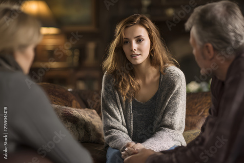 Adult child talks with parents in cozy living room