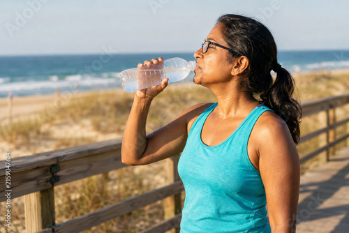 Woman Drinking Water on Beach Boardwalk in Summer Heat