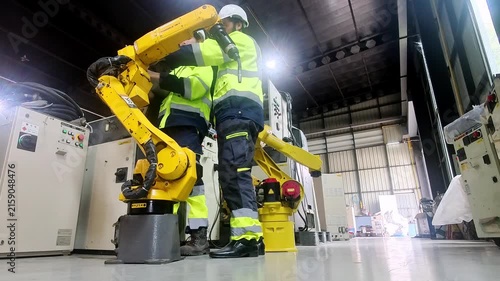 Industrial robot arm and technicians in a modern factory setting