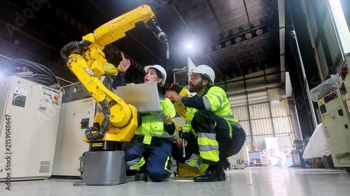 Engineers collaborate on industrial robot maintenance in a modern factory setting