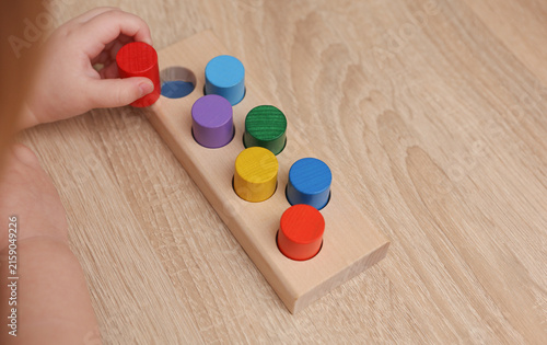 Fotografie A toddler plays with a wooden color sorter