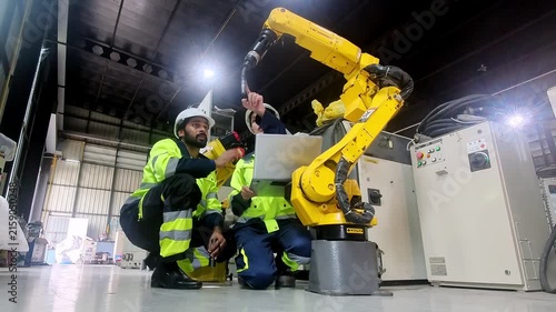 Engineers collaborate on industrial robot arm maintenance in a modern factory setting