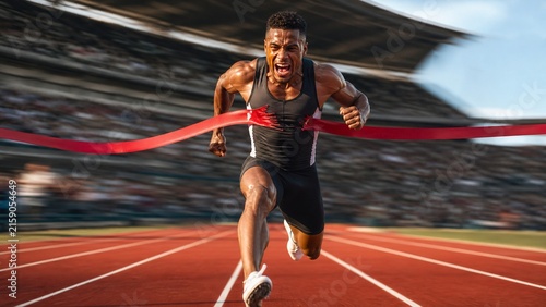 Powerful Sprinter Breaking the Finish Line Ribbon in a Packed Stadium