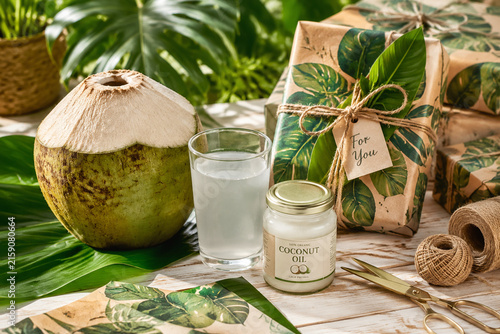 Tropical gift wrapping with whole coconut, coconut water, coconut oil, banana leaves, natural twine, summer refreshment.